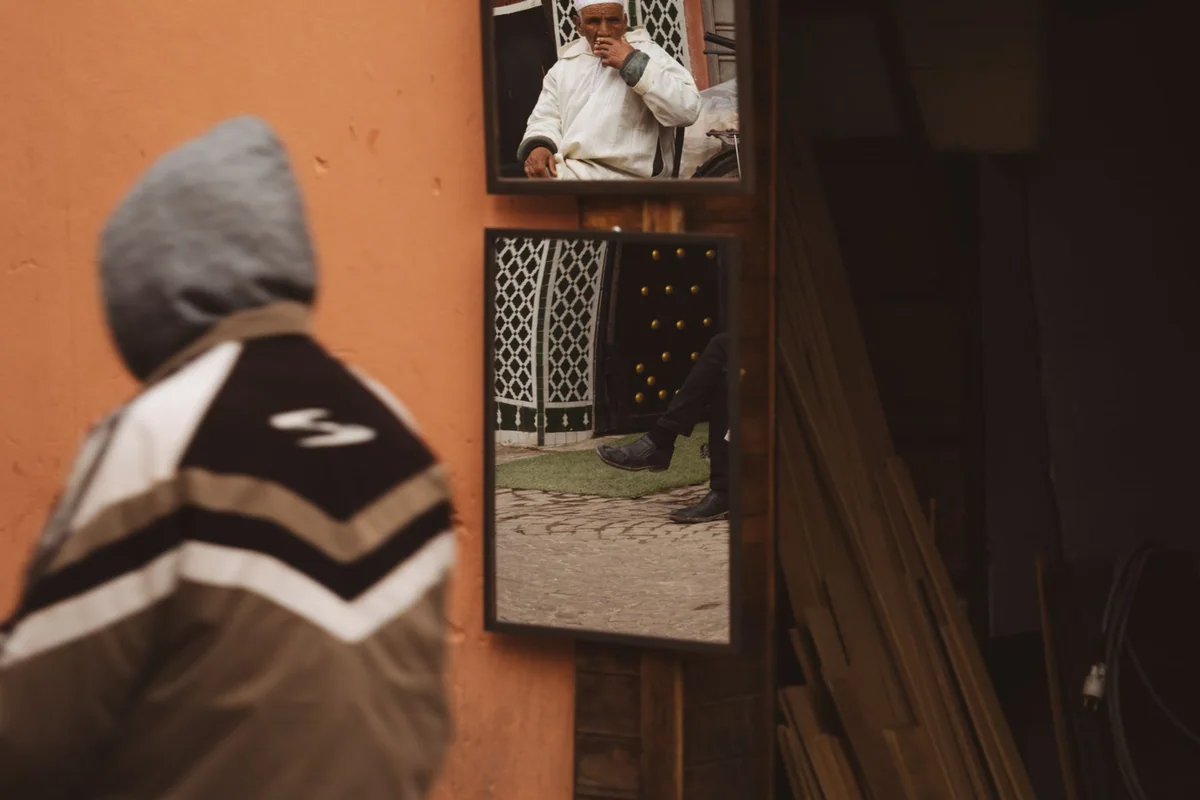 A leaning floor mirror secured beside a dresser in a small room