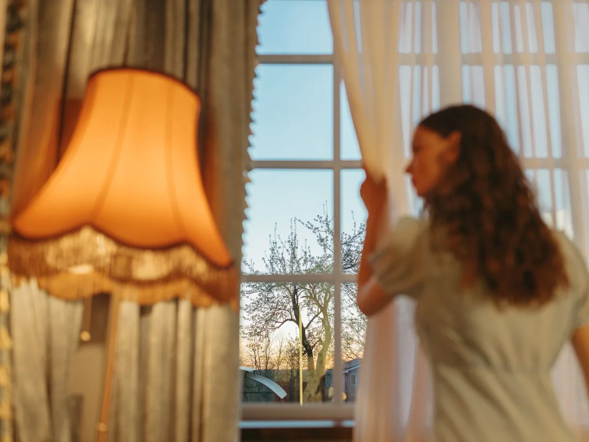Layered dark curtains covering a bedroom window for daytime sleep